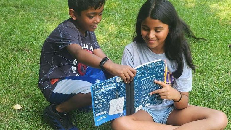 Two children reading a copybook